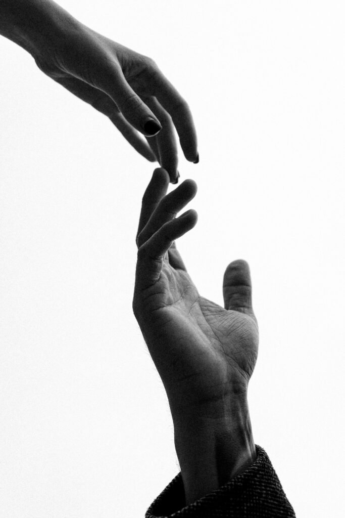 Two hands reaching out, captured in black and white style, symbolizing connection.