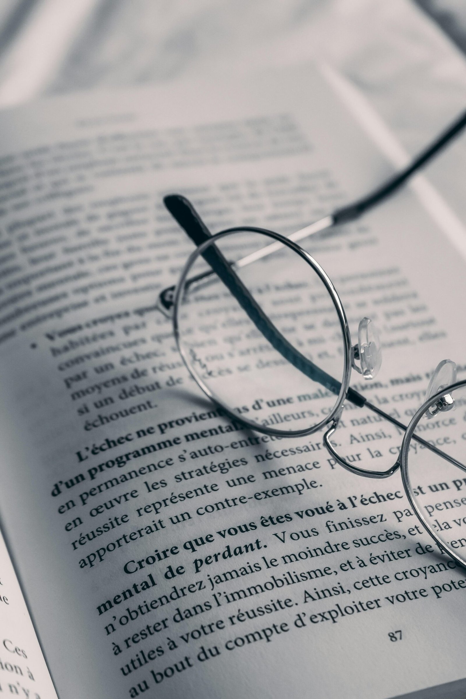 Close-up of reading glasses resting on an open book, emphasizing literature and contemplation.