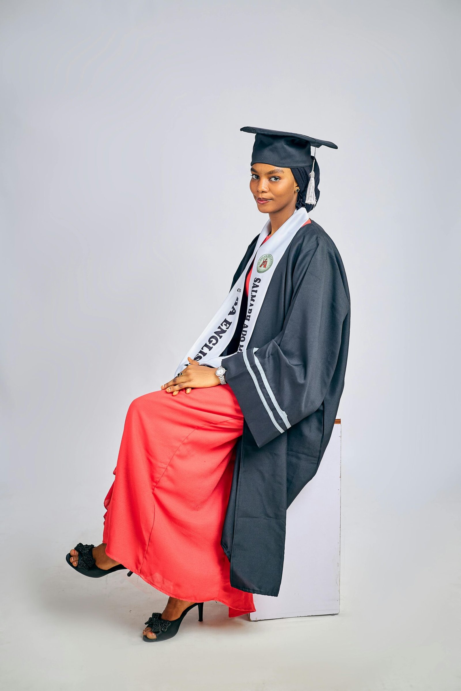 Portrait of a seated graduate in cap and gown, exuding pride and achievement.