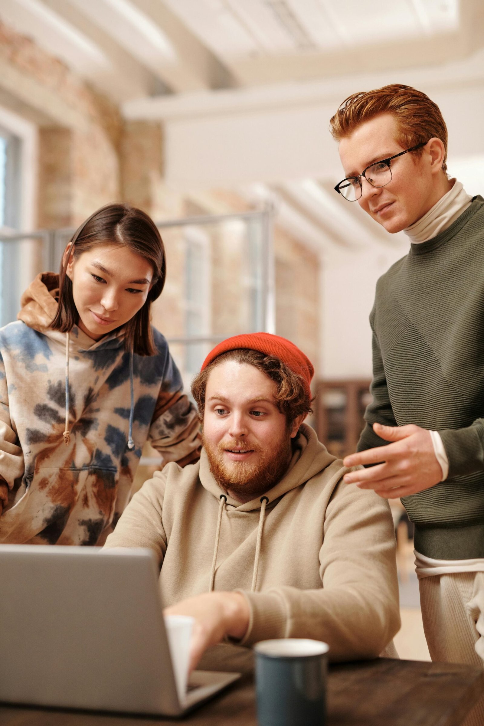 Diverse group of young adults working together on a laptop in a stylish office setting.