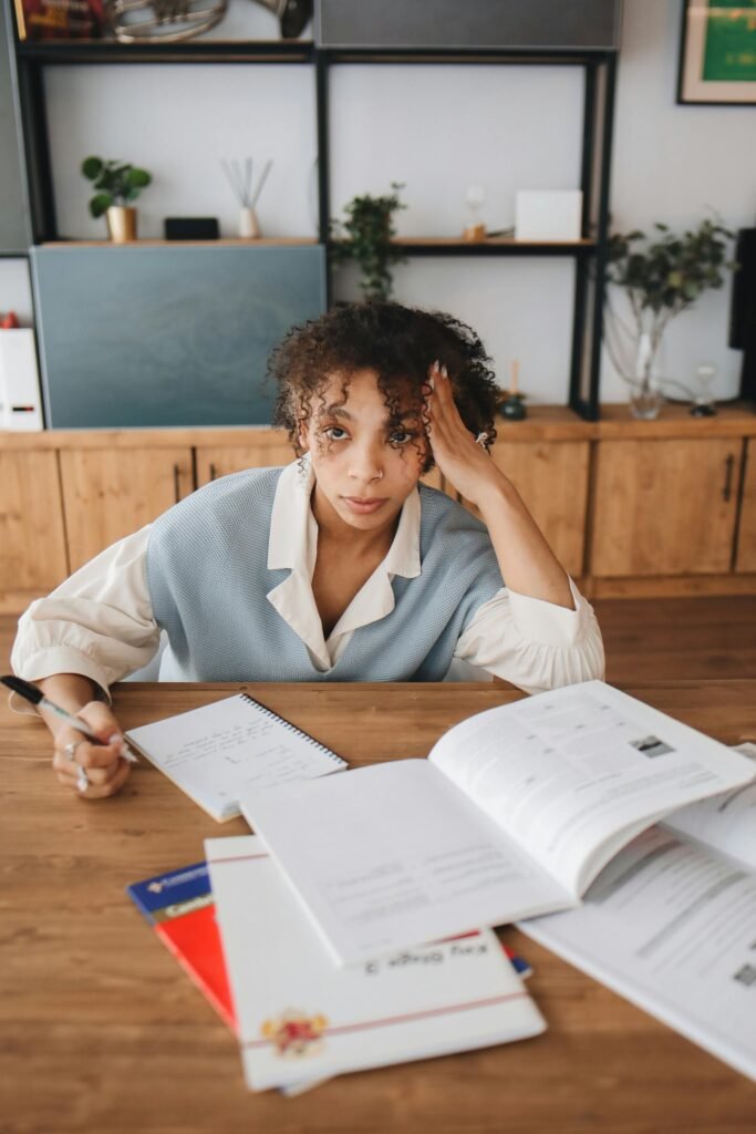 A young woman deeply engrossed in studying at a desk, surrounded by books and notebooks.