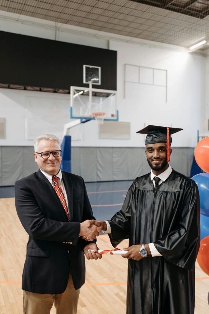 Graduating student shaking hands with school director in a gymnasium.